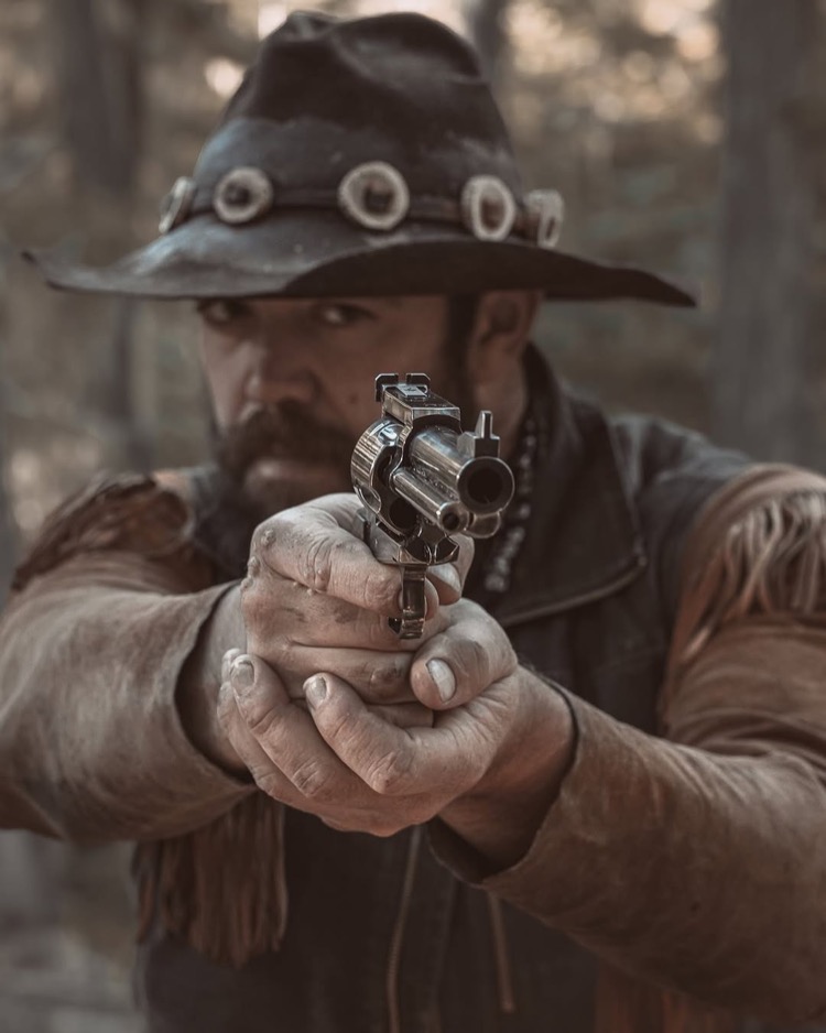 カウボーイスタイルでリボルバーを構える男性
