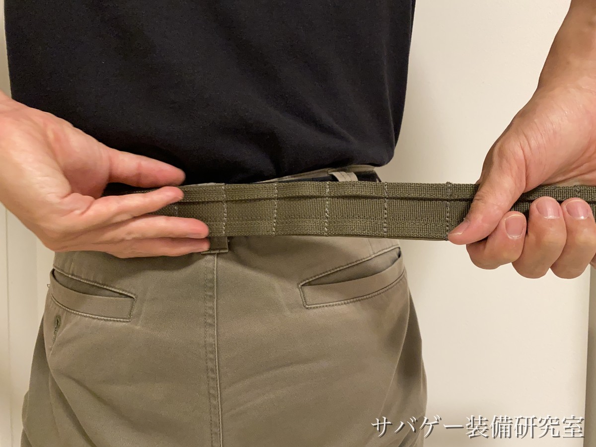 腰に巻いたアウターベルトの長さを両手で合わせているところ
