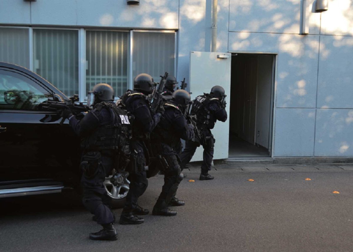 建物へ突入する特殊部隊SATの隊員4人(紺の活動服に黒の防護装備とMP5・警察庁の訓練写真)